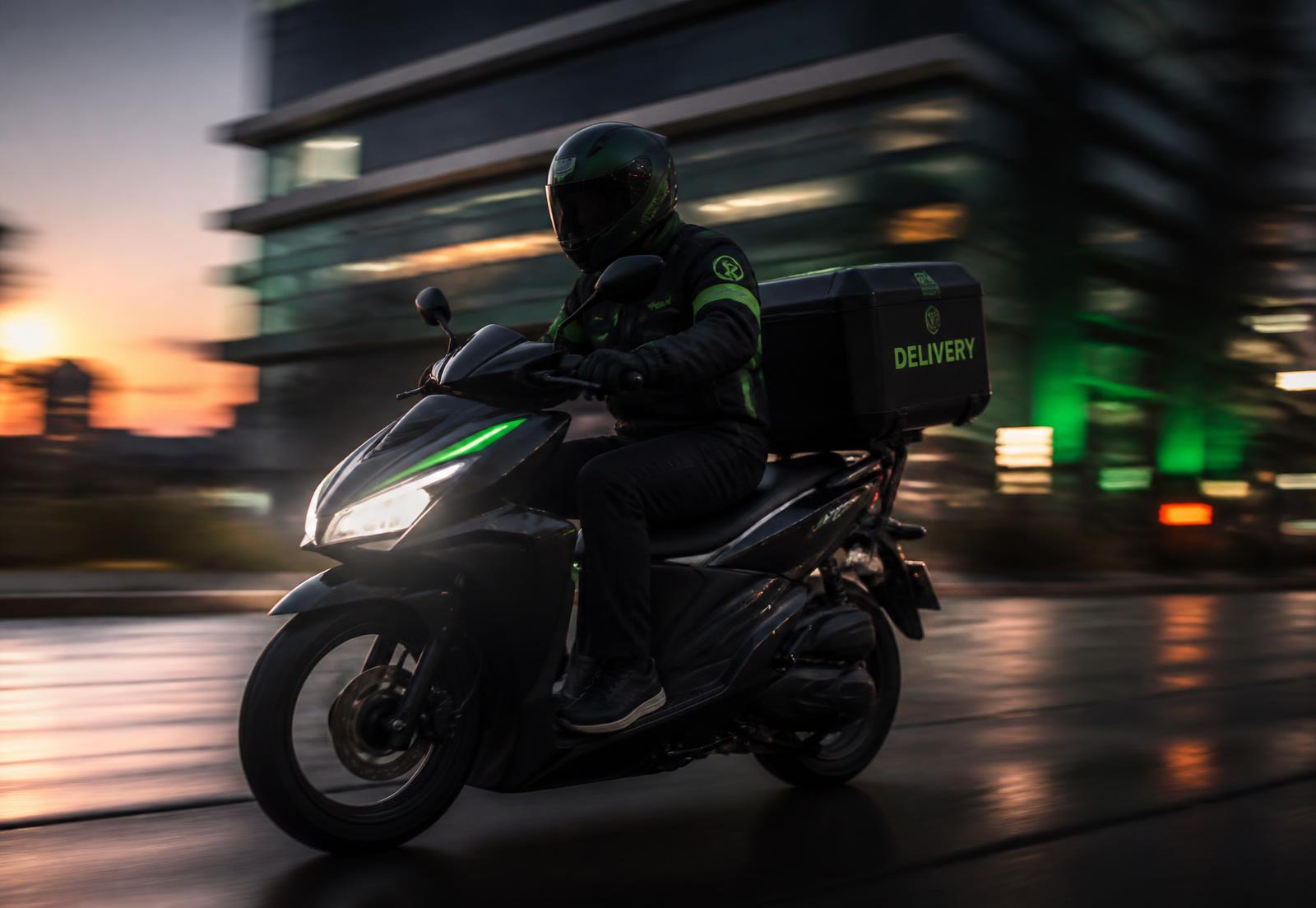 Livreur ScootFast sur un scooter équipé d'un top case en ville